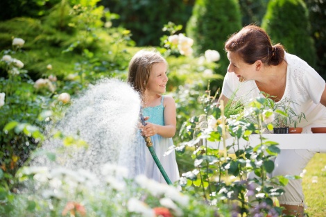 Girl and granny watering flowers in garden